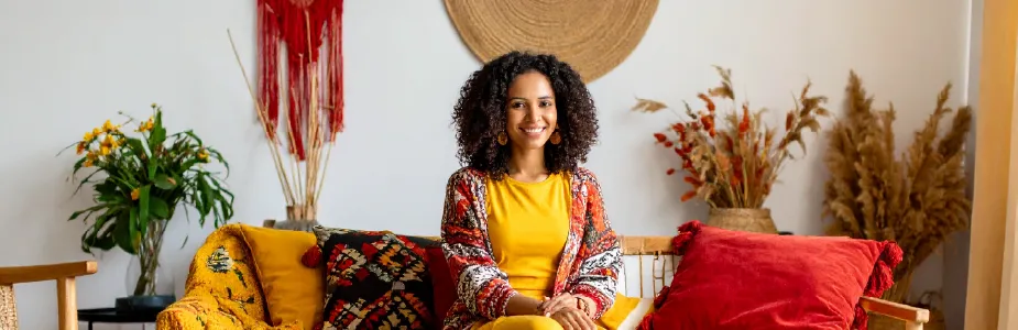 Mulher brasileira com expressão leve usando roupas casuais e confortáveis, rodeada por tons suaves com toques de vermelho, amarelo e preto.