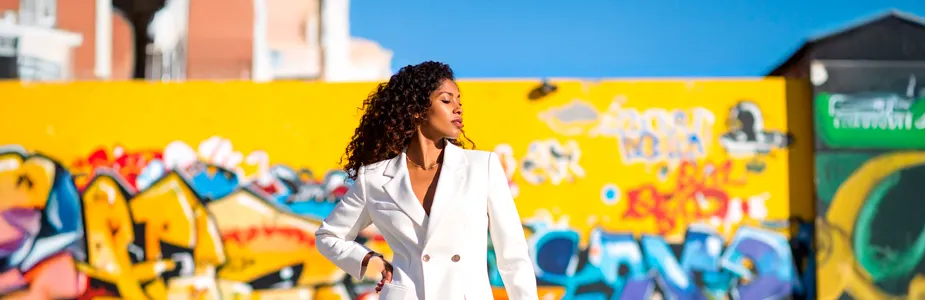 Mulher estilosa adaptando looks de inverno para o calor em cenário urbano, com peças leves e cores vibrantes.