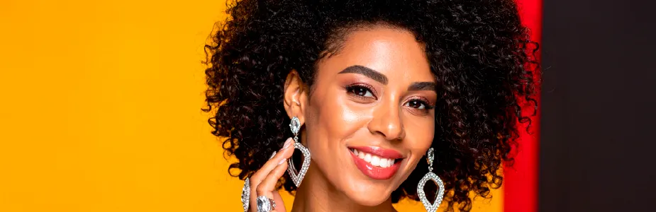 Mulher brasileira exibindo acessórios prateados com elegância, em ambiente moderno com toques de vermelho, amarelo e preto.